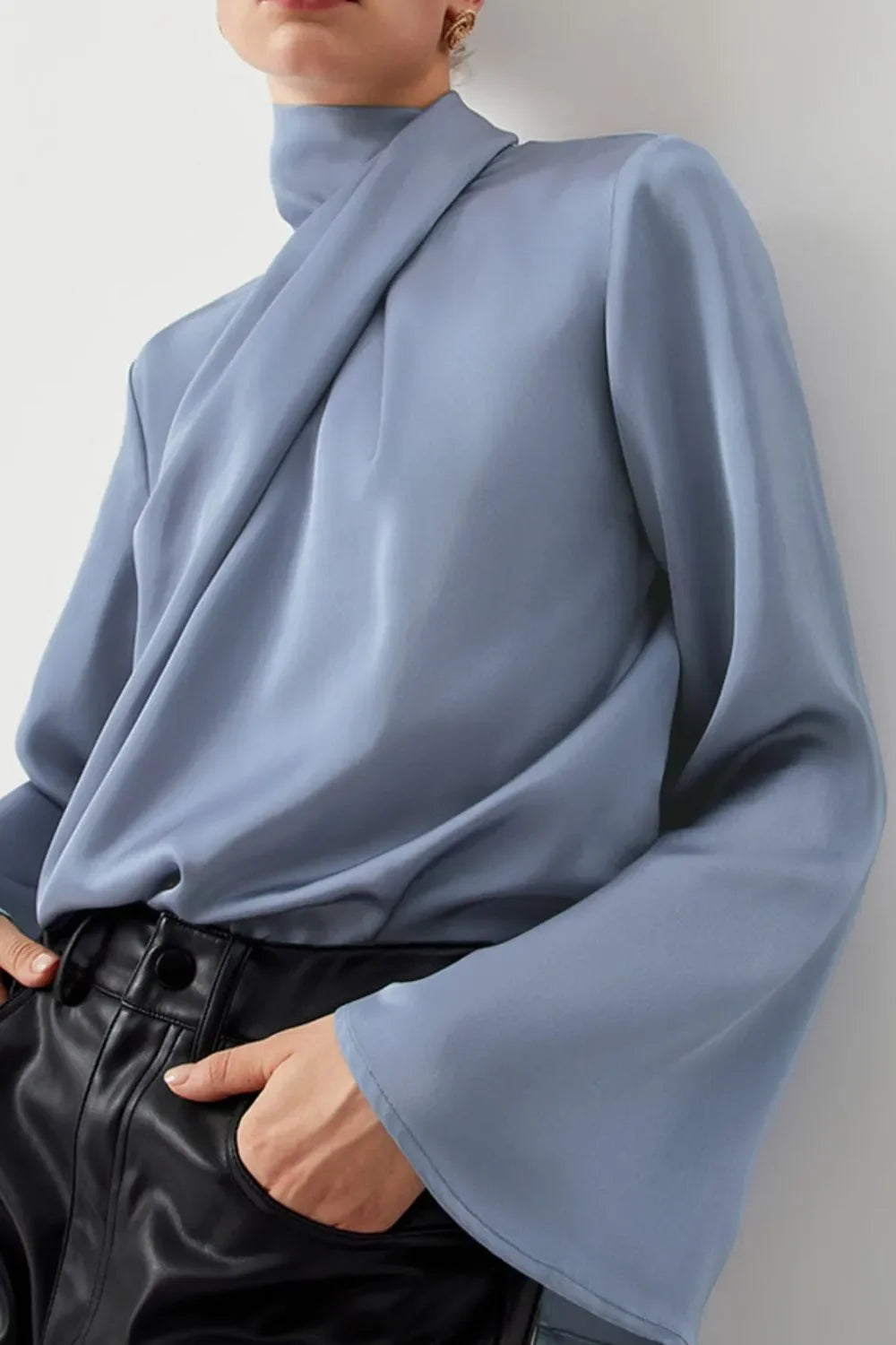 Woman wearing light blue satin blouse with flared sleeves and black leather pants
