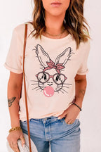 Woman wearing light pink graphic tee with cartoon bunny, glasses, and bow, paired with jeans.