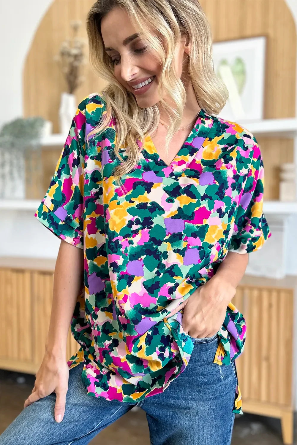 Woman wearing colorful floral print V-neck blouse and blue jeans, casual fashion style