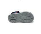 Gray sole of a sport sandal with textured grip, blue upper, and velcro strap visible