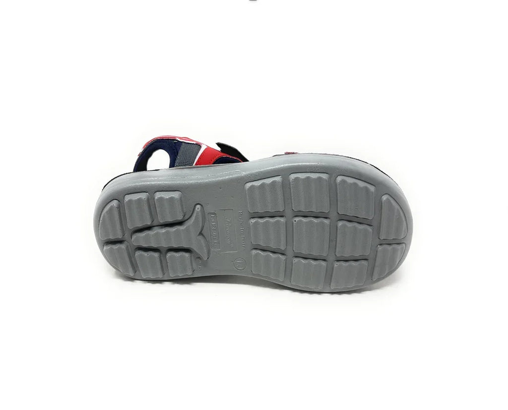 Gray rubber sole of a kid's sandal with red and navy blue upper straps, non-slip tread