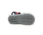 Gray rubber sole of a kid's sandal with red and navy blue upper straps, non-slip tread