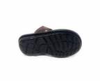 Black textured sole of a brown men's sandal, slip-resistant footwear on white background