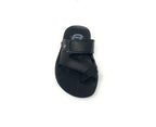 Black slip-on sandal with adjustable strap and textured footbed on white background