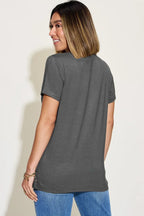 Woman wearing a short sleeve charcoal grey t-shirt and blue jeans, viewed from the back.