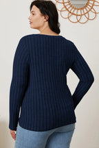 Plus size woman in a navy blue ribbed long sleeve sweater and light wash jeans
