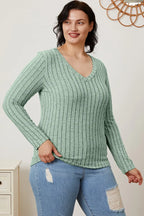 Woman in mint green ribbed long sleeve V-neck top and ripped blue jeans