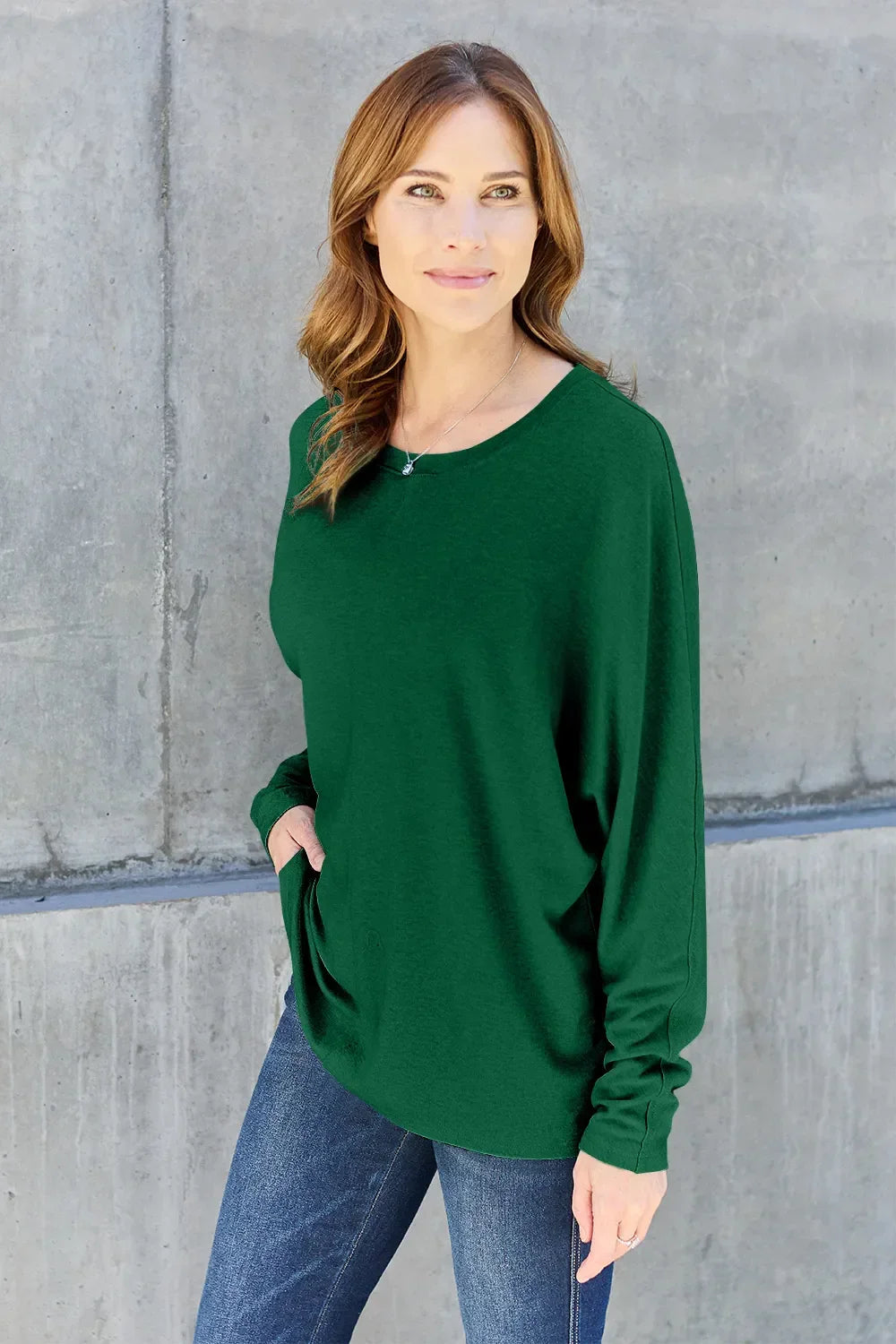 Woman wearing a green long sleeve top and blue jeans, casual outfit