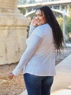 Smiling woman in casual white long sleeve top and blue jeans outdoors