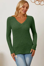Woman wearing green ribbed knit V-neck sweater and light blue jeans