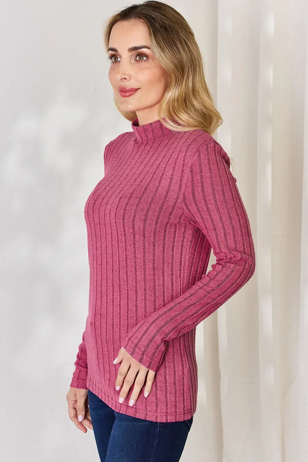 Woman wearing a long sleeve ribbed pink mock neck sweater, casual fashion top