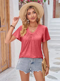 Woman in casual summer outfit with pink V-neck T-shirt, denim shorts, straw hat and clutch