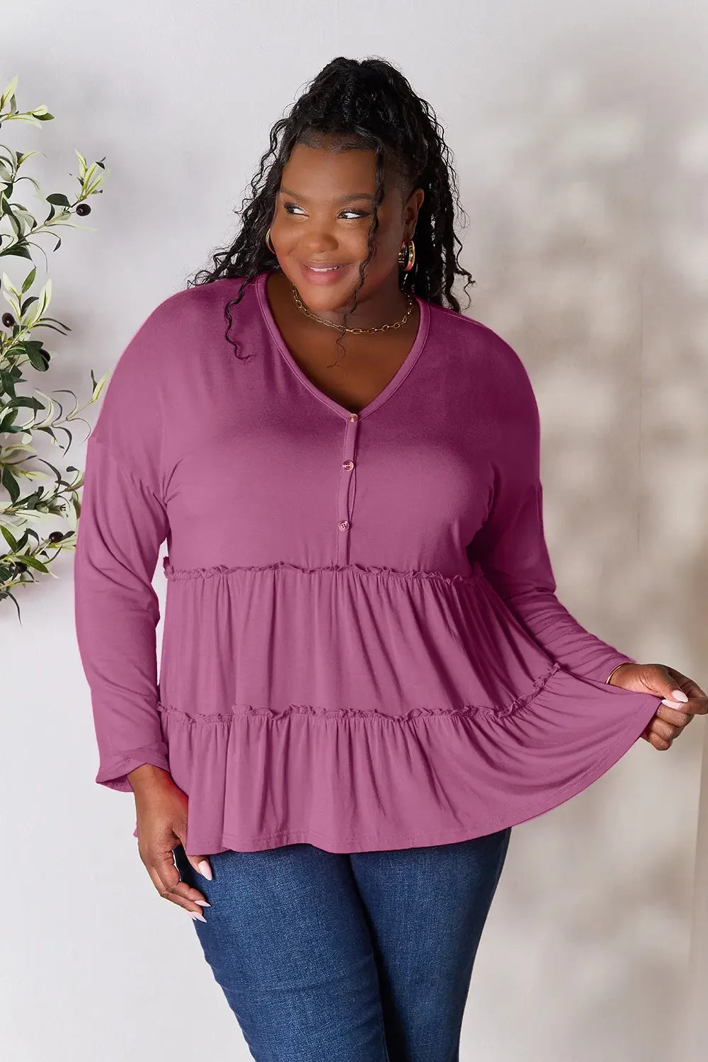 Smiling woman in a mauve long sleeve tiered tunic top and blue jeans, casual fashion