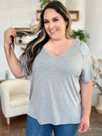Smiling woman in casual plus size gray t-shirt and blue jeans indoors