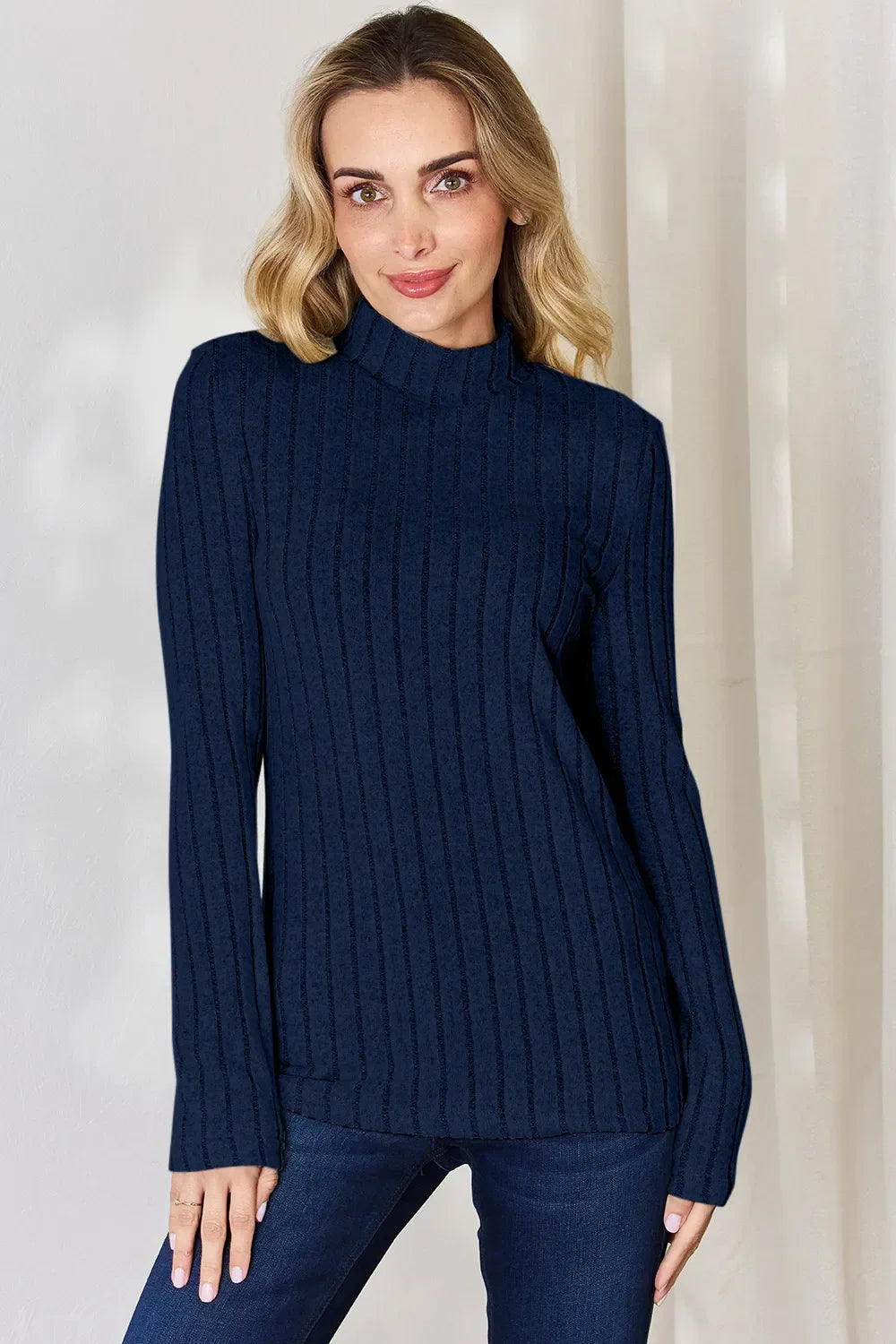 Woman wearing a navy blue ribbed knit sweater with mock neck and long sleeves