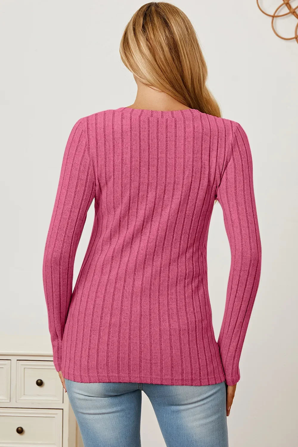 Back view of woman in pink ribbed knit sweater and light blue jeans