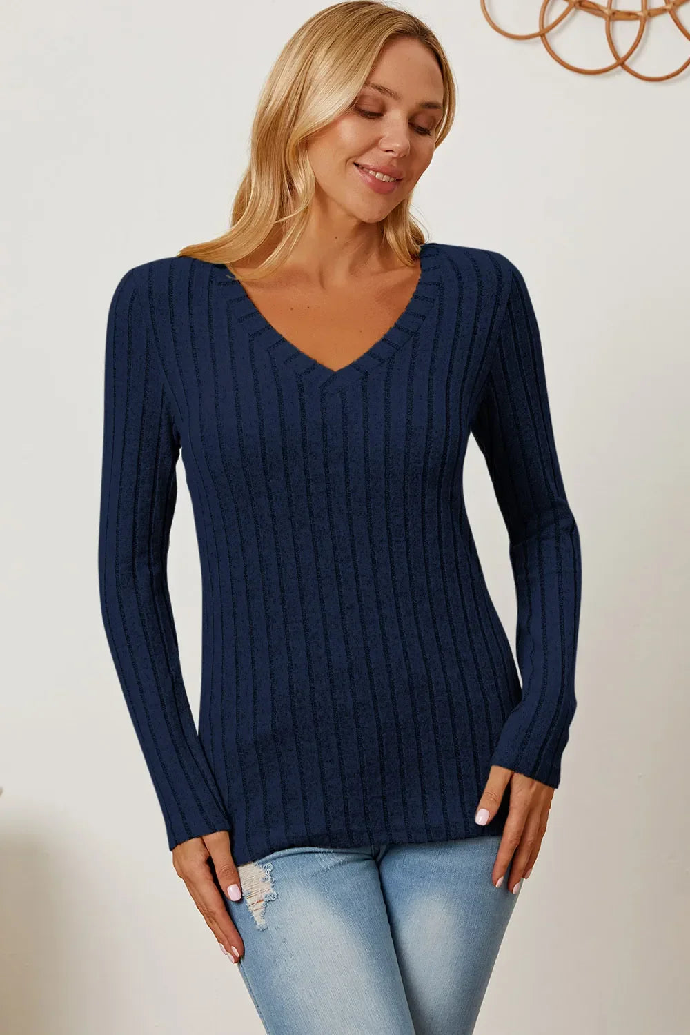 Woman wearing a navy blue ribbed V-neck sweater and light wash jeans