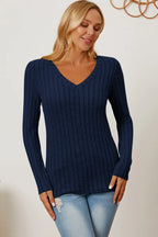 Woman wearing a navy blue ribbed V-neck sweater and light wash jeans