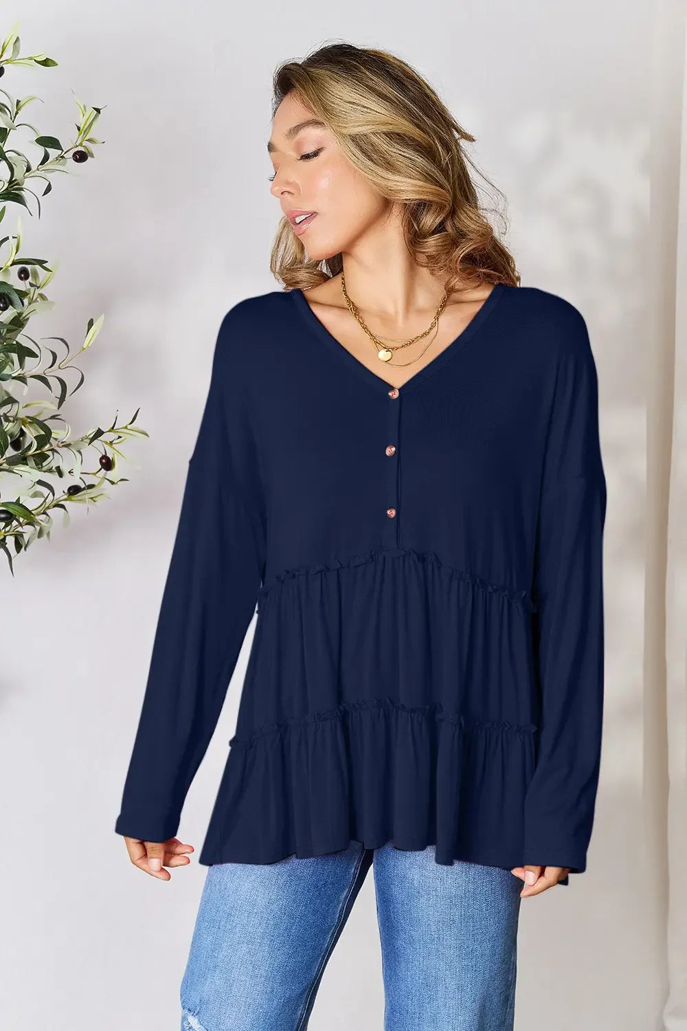 Woman wearing navy blue long sleeve V-neck blouse with buttons and blue jeans