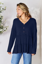 Woman wearing navy blue long sleeve V-neck blouse with buttons and blue jeans