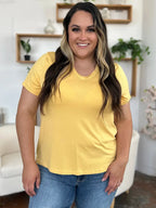 Woman wearing a yellow V-neck T-shirt and blue jeans in a modern living room