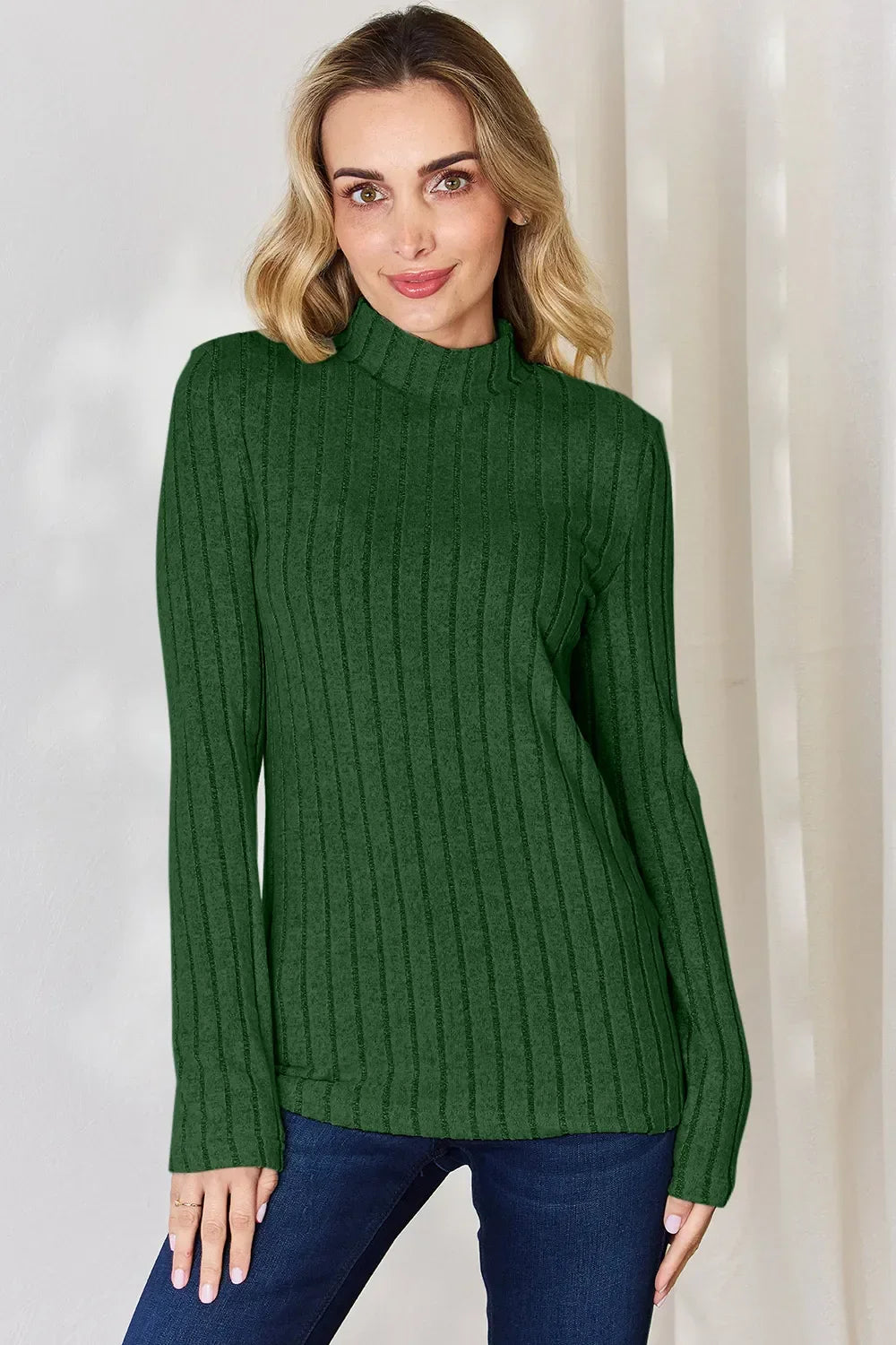 Woman in green ribbed knit sweater with mock neck and blue jeans, casual fashion outfit