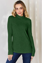 Woman in green ribbed knit sweater with mock neck and blue jeans, casual fashion outfit