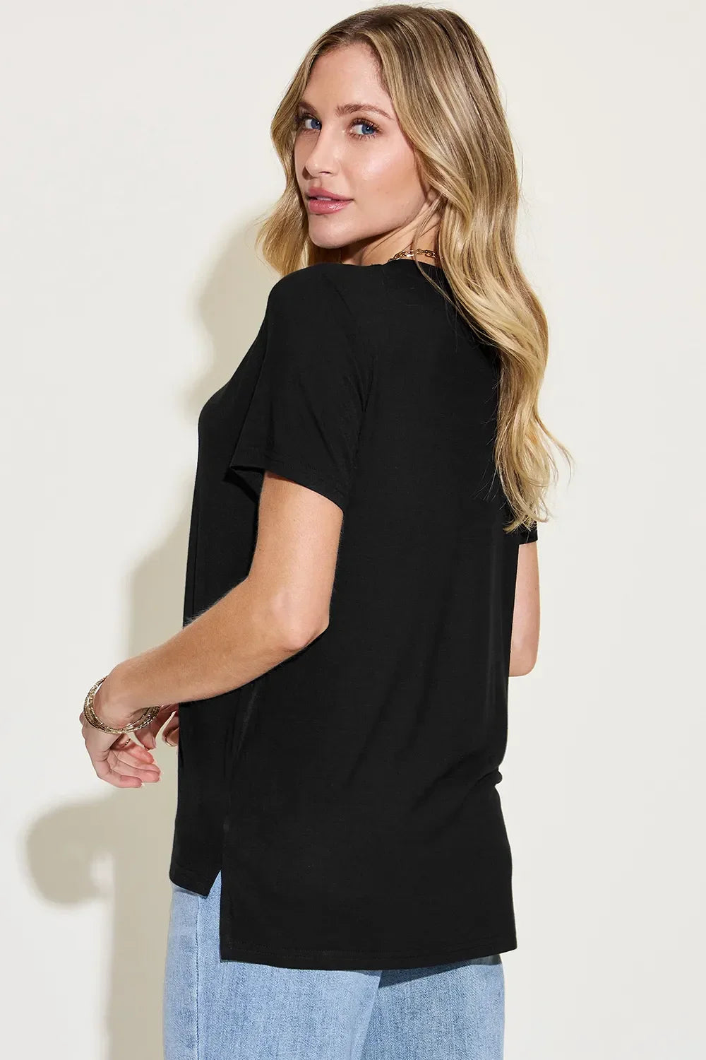 Woman in black short sleeve t-shirt and light blue jeans, side view, casual outfit