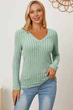 Woman wearing mint green ribbed knit long sleeve V-neck top and light blue jeans