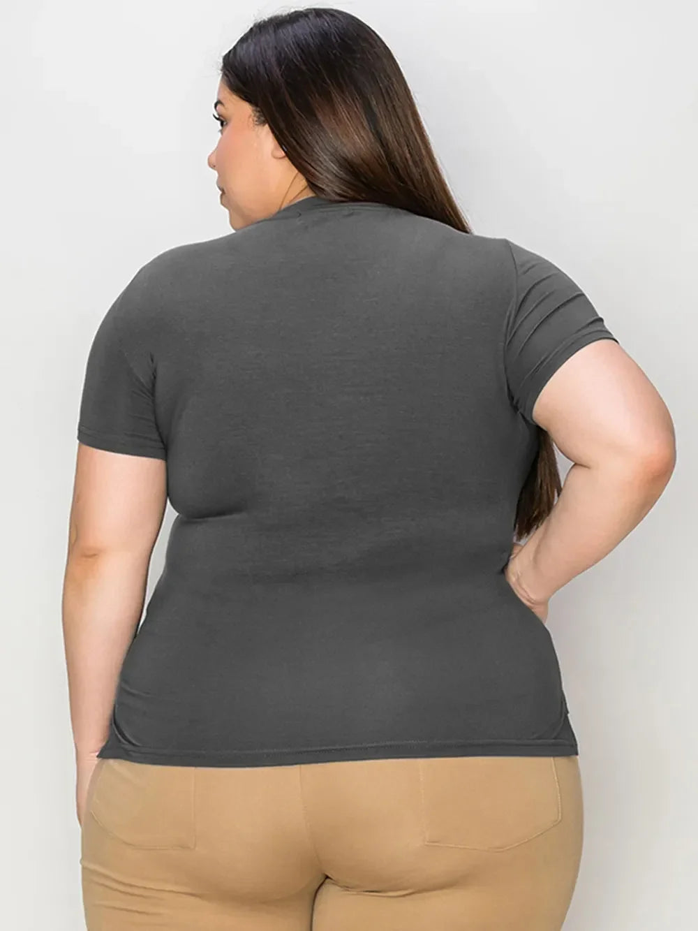 Plus size woman in charcoal gray short sleeve t-shirt and beige pants, back view