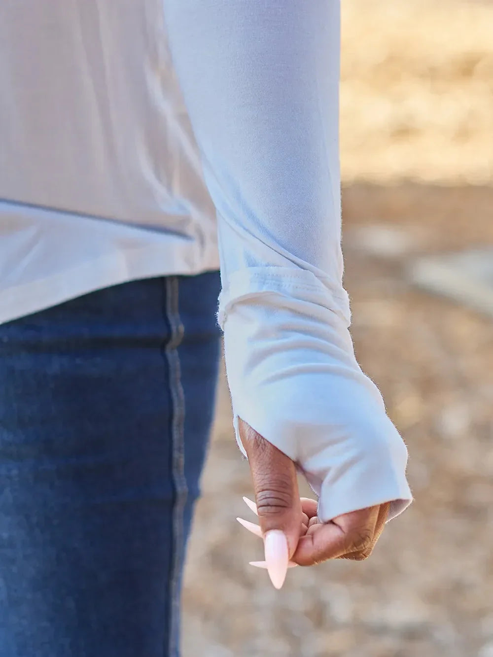 Light blue long sleeve top with thumb hole, paired with blue jeans outdoors