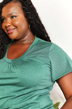 Woman in green short sleeve V-neck top with gold chain necklace, casual fashion