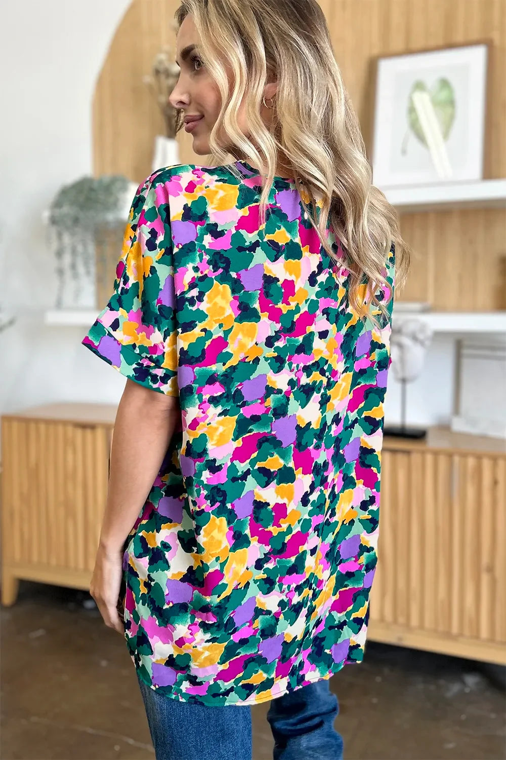 Woman wearing colorful floral print short sleeve blouse and blue jeans indoors