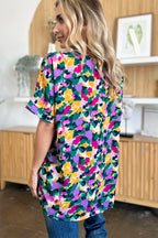 Woman wearing colorful floral print short sleeve blouse and blue jeans indoors