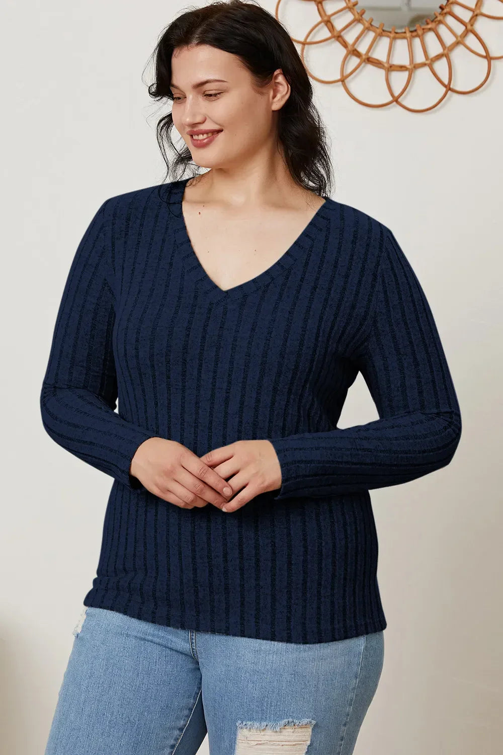 Woman in navy blue ribbed V-neck sweater and ripped light wash jeans