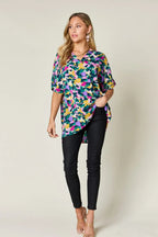 Woman wearing a colorful abstract print blouse with black skinny pants and heels