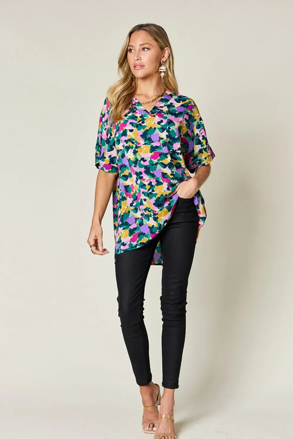 Woman wearing a colorful abstract print blouse with black skinny pants and heels
