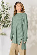 Woman wearing ribbed sage green knit sweater tunic with long sleeves and beige pants