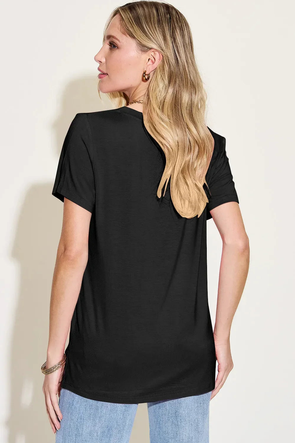 Woman modeling casual black short sleeve t-shirt and light blue jeans, back view
