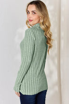 Woman wearing sage green ribbed long sleeve sweater and dark denim jeans