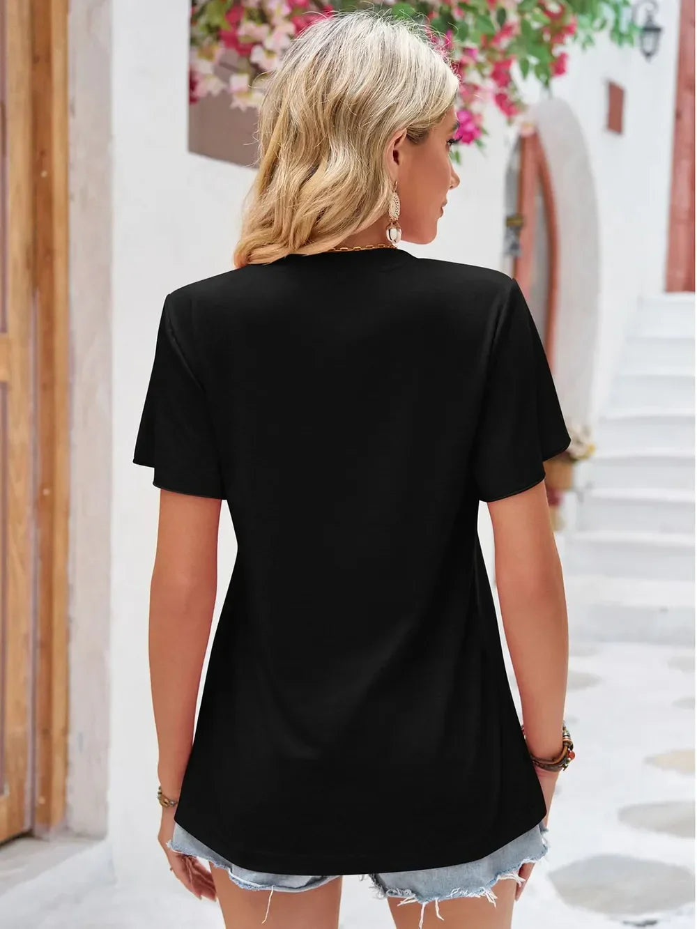 Woman in black short-sleeve t-shirt and denim shorts outdoors, summer casual outfit