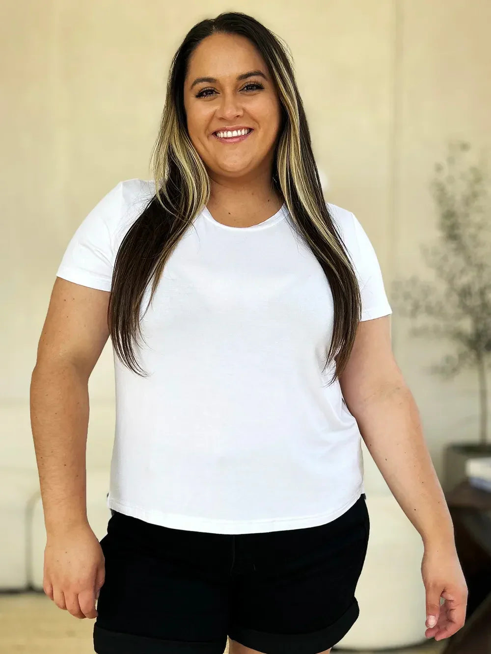 Smiling woman in a white t-shirt and black shorts, casual summer outfit