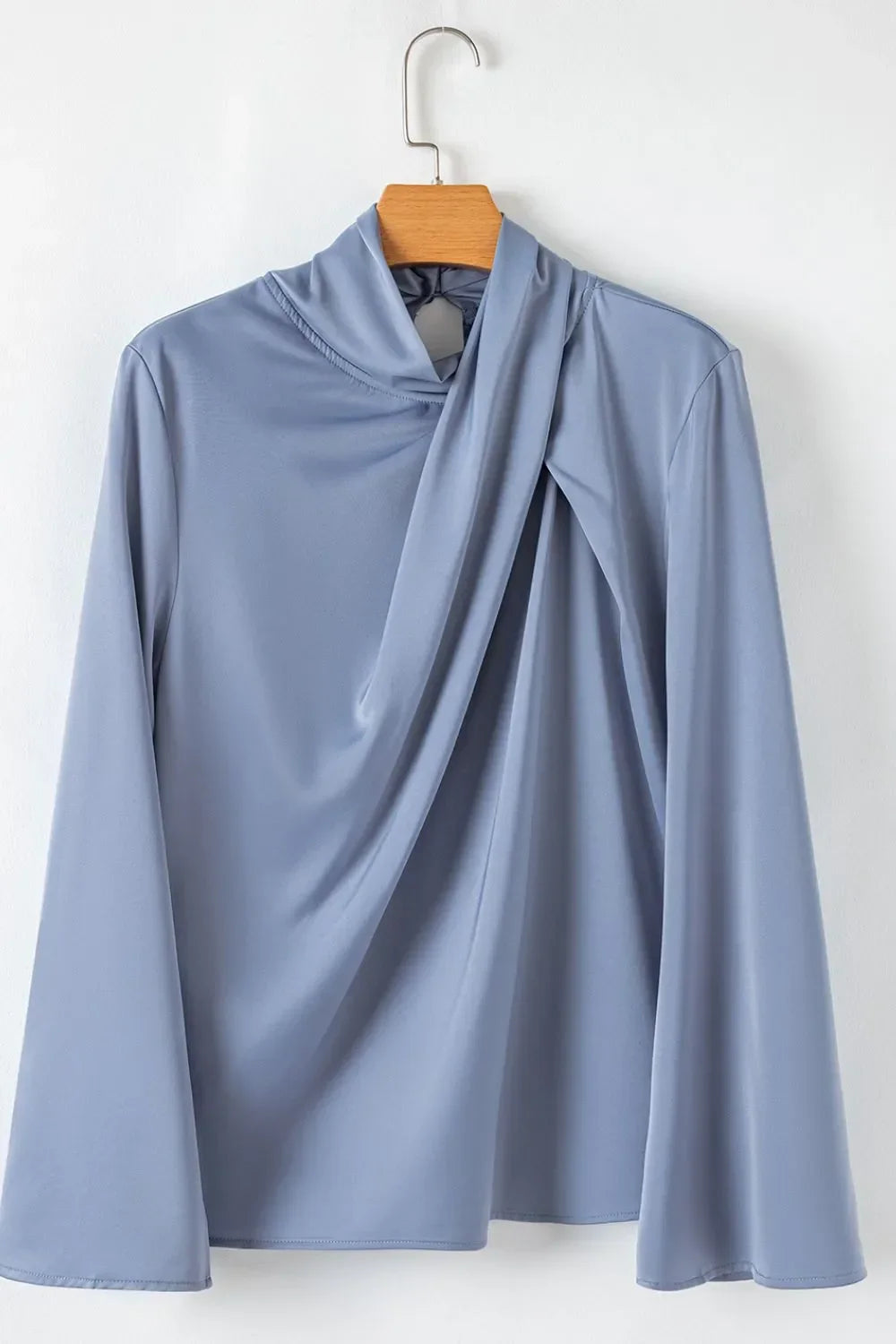 Light blue long sleeve draped blouse with a unique twisted neckline on hanger