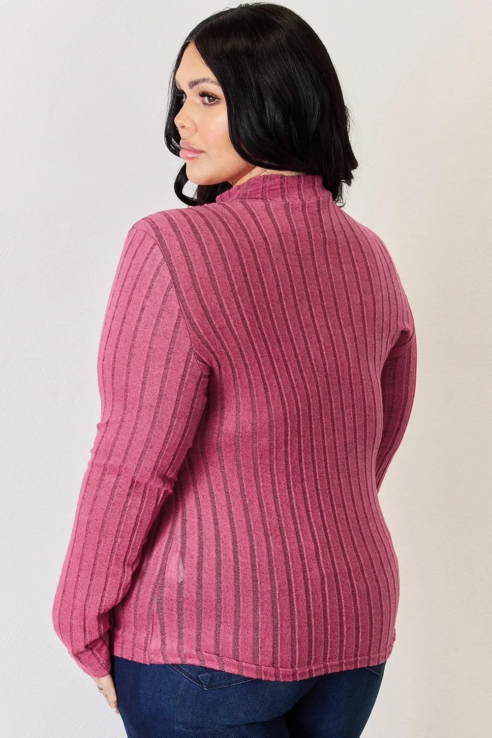 Woman in a pink ribbed long sleeve top and dark jeans, back view