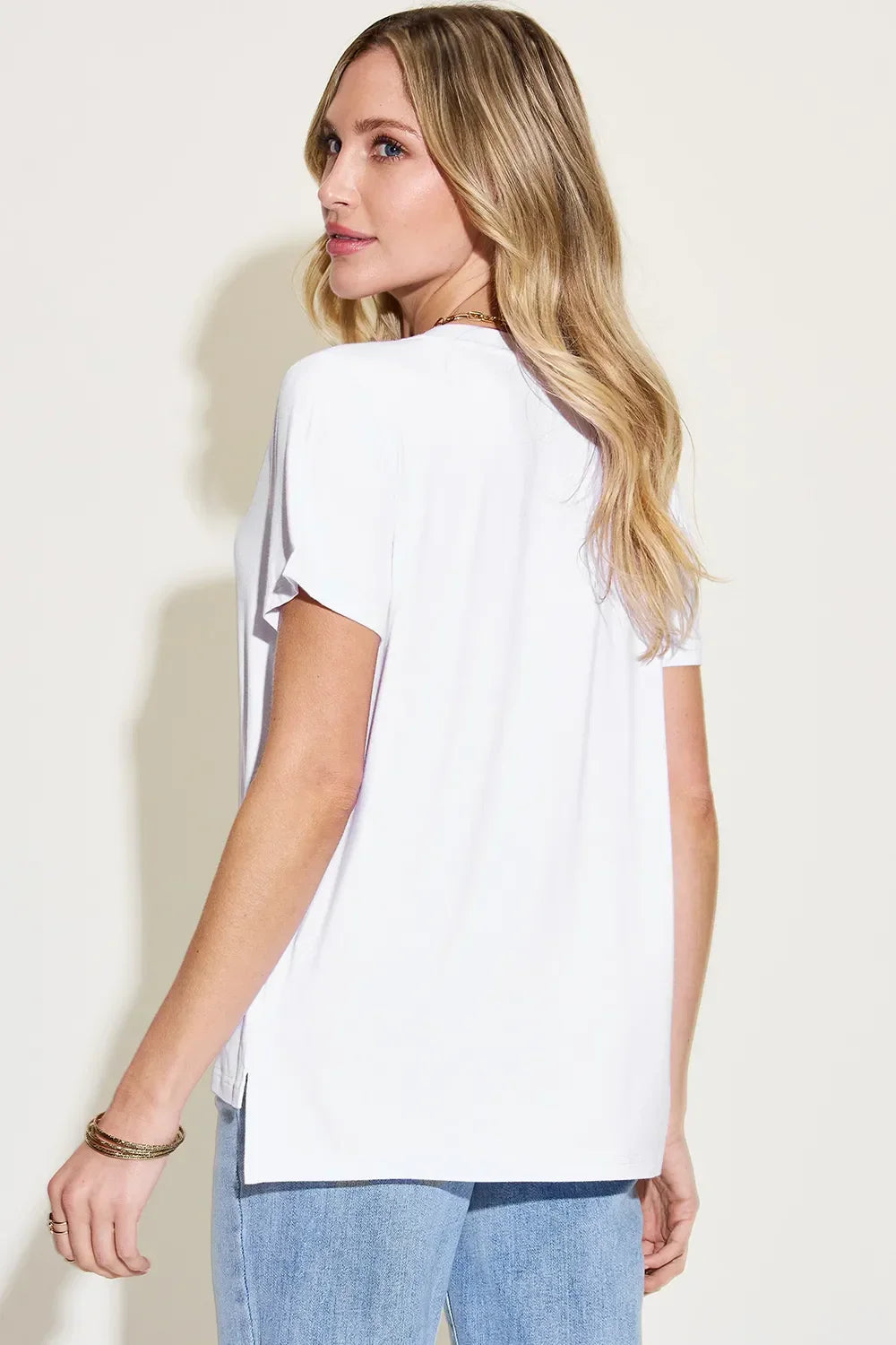 Woman wearing a casual white short sleeve t-shirt and light blue jeans, back view
