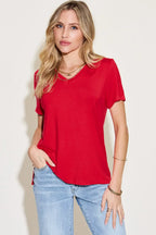 Woman wearing a red V-neck T-shirt with light blue jeans and gold jewelry