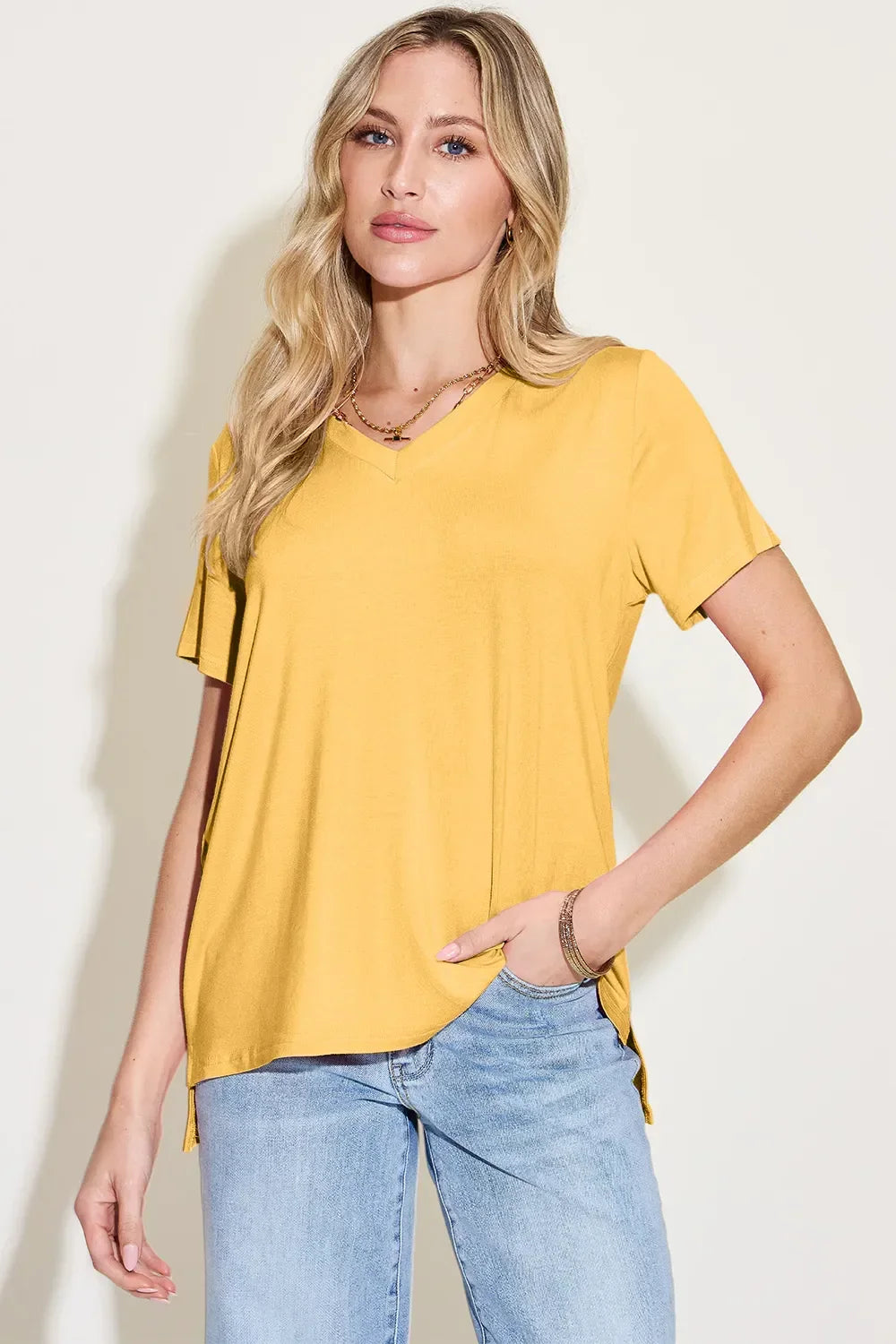 Woman wearing a casual yellow V-neck short sleeve t-shirt and light blue jeans