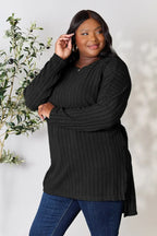 Woman wearing a black ribbed knit sweater with long sleeves and blue jeans