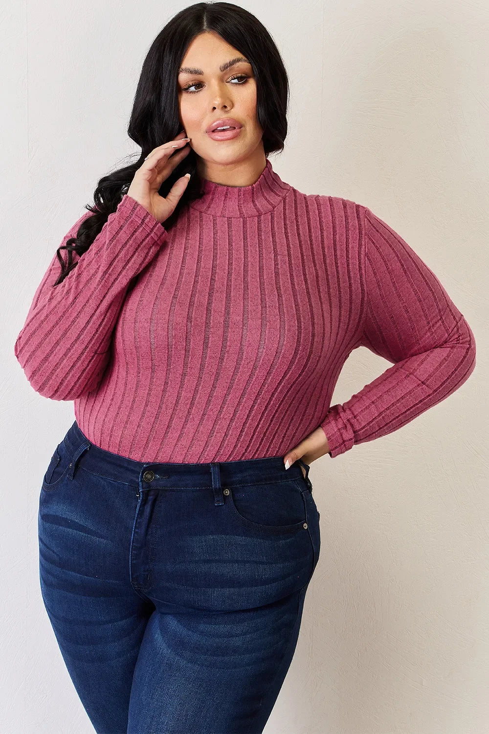 Woman in a ribbed pink long sleeve turtleneck and dark blue jeans