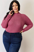 Woman in a ribbed pink long sleeve turtleneck and dark blue jeans